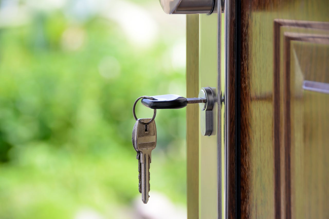 Services Key inserted in door lock against a blurred green background, symbolizing security and real estate.